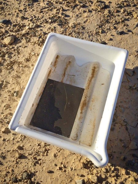 Darkroom tray with a tintype and a lot of sand and dirt.