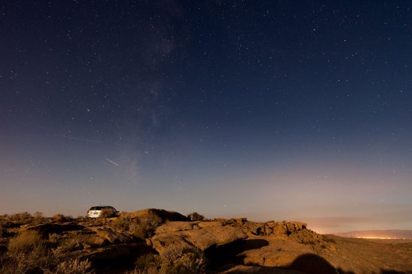 The rising nearly-full moon lights up the ridge I camped on, and my car, with the Milky Way, an airplane or two, and a distant town in the background.