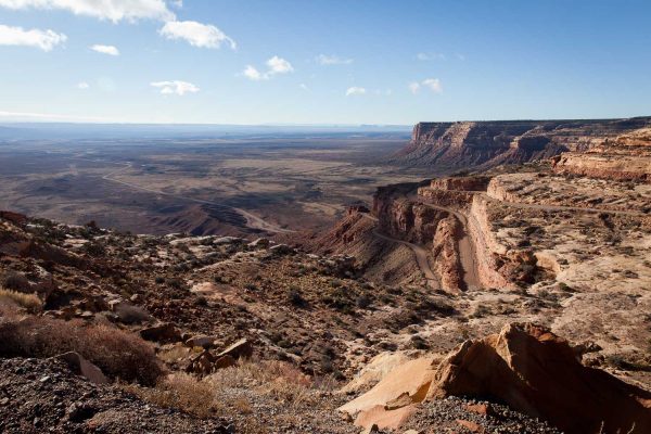 The Moki Dugway (switchbacks in the road) and Muley Point (the mesa top in the distance on the left) frame the valley that leads off to famed Monument Valley in the distance.