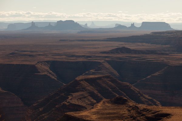 View from Muley Point: The San Juan River meanders deep out of sight through the Goosenecks area (foreground) while the buttes and mesas of Monument Valley rise in the distance.