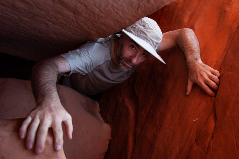 Mark Edward Dawson crawls up through a narrow crack in the walls of Fifty Mile Canyon in southern Utah.